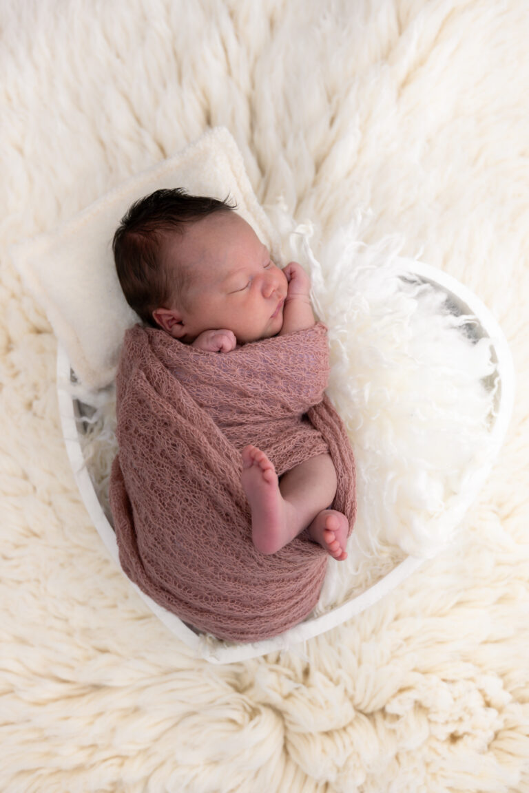 Photographe naissance Jura Besançon – nouveau-né emmailloté sur une fourrure blanche
