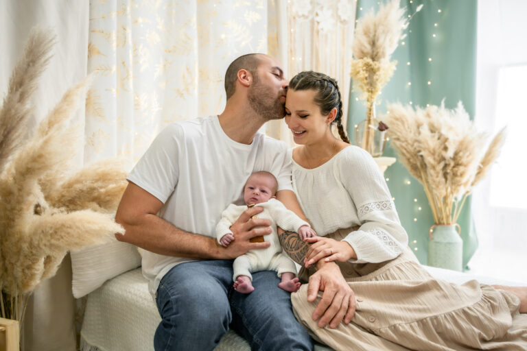 Photographe naissance Jura Morez Lons-le-Saunier – parents assis avec bébé dans un décor bohème