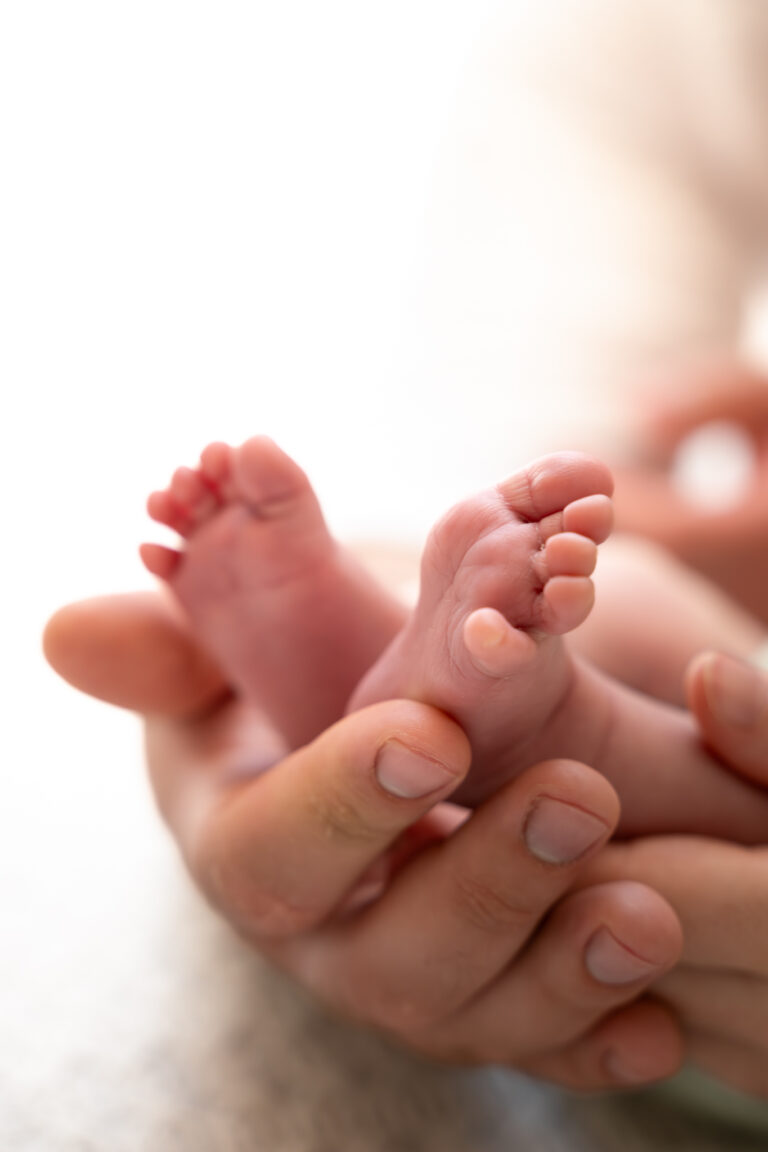 Photographe naissance Jura Morez Champagnole – petits pieds de bébé dans la main de ses parents
