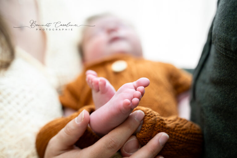 Photographe naissance Morez Jura Suisse romande – petits pieds de bébé dans les mains de ses parents