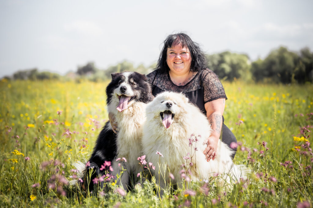 Photographe animaux chien Morez Jura Genève Lausanne Champagnole Lons-le-Saunier Besançon – femme entourée de ses deux chiens dans un pré fleuri